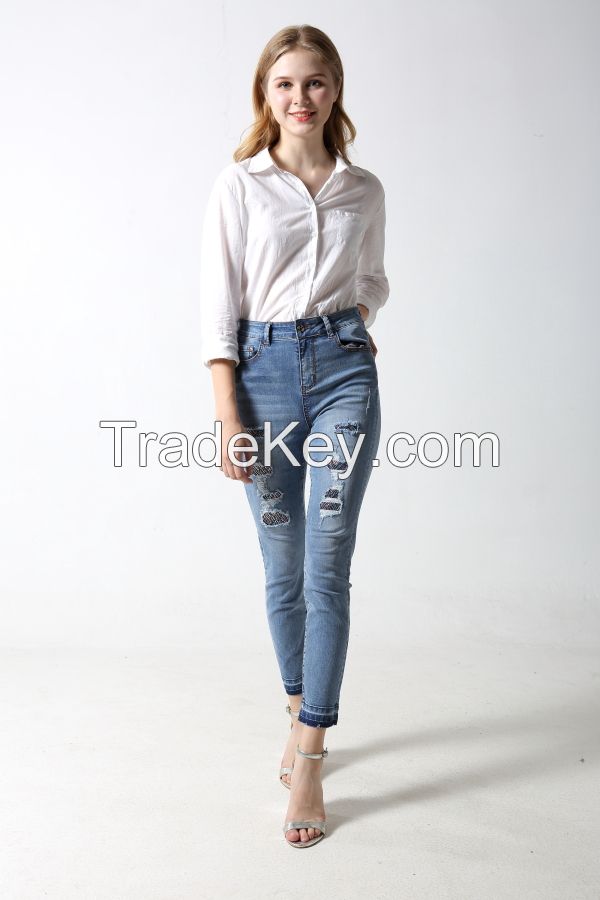 Woman's slim denim jeans with distress and patches with rhinestones