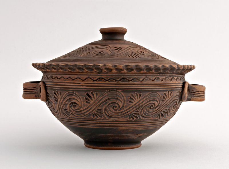 Ceramic bowl with handles and lid made of red clay.