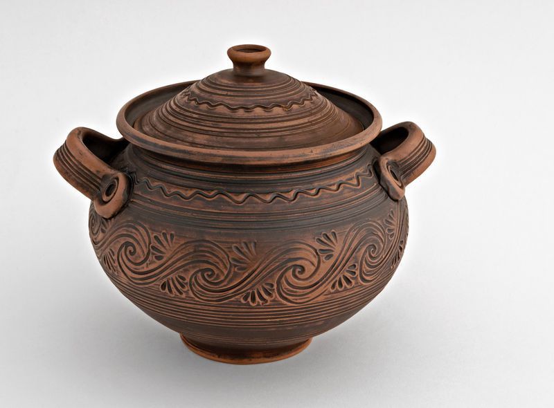 Big brown ceramic pot with lid made of red clay.